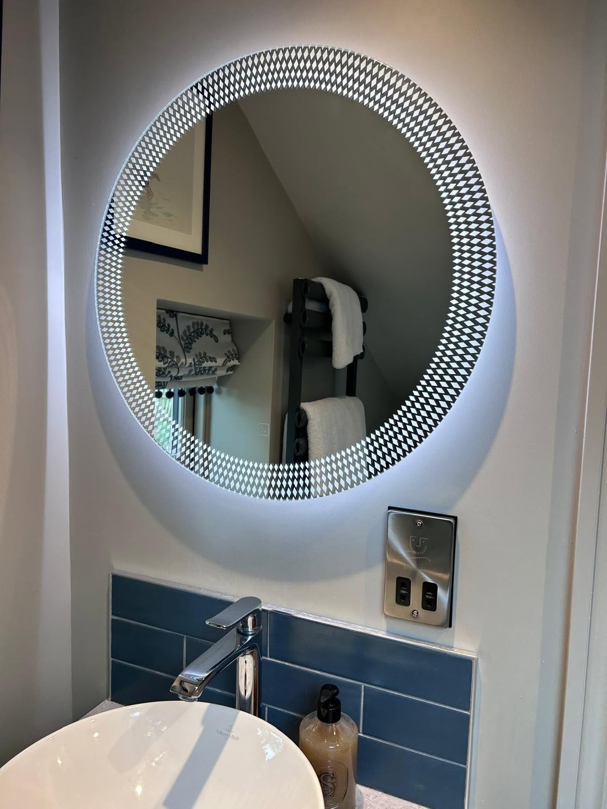 Round illuminated bathroom mirror above a basin