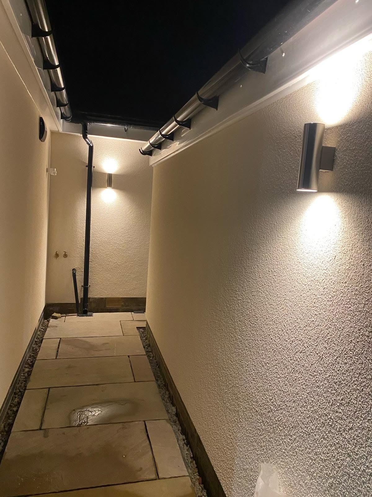 Side passage lit at night by up and down wall lights