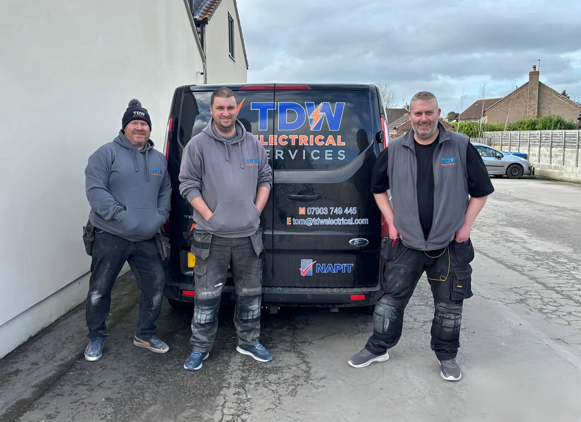 Three of the TDW team in branded workwear in front of the TDW van