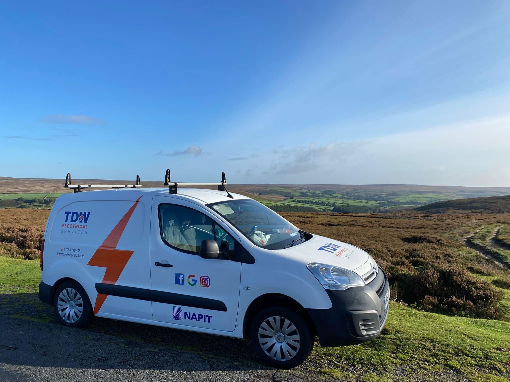 White TDW van parked on open moorland under a blue sky