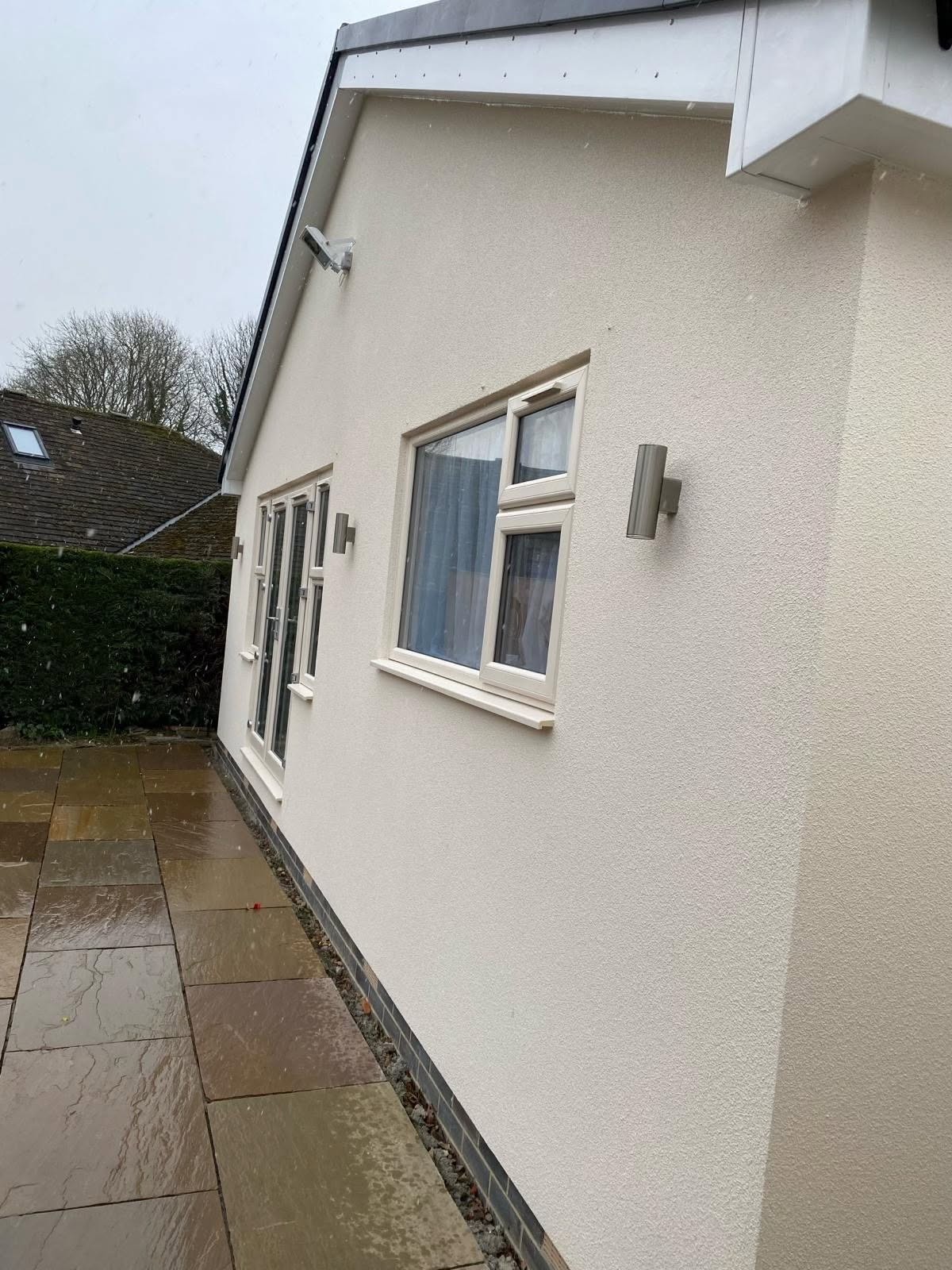 Stainless steel wall lights on a rendered bungalow