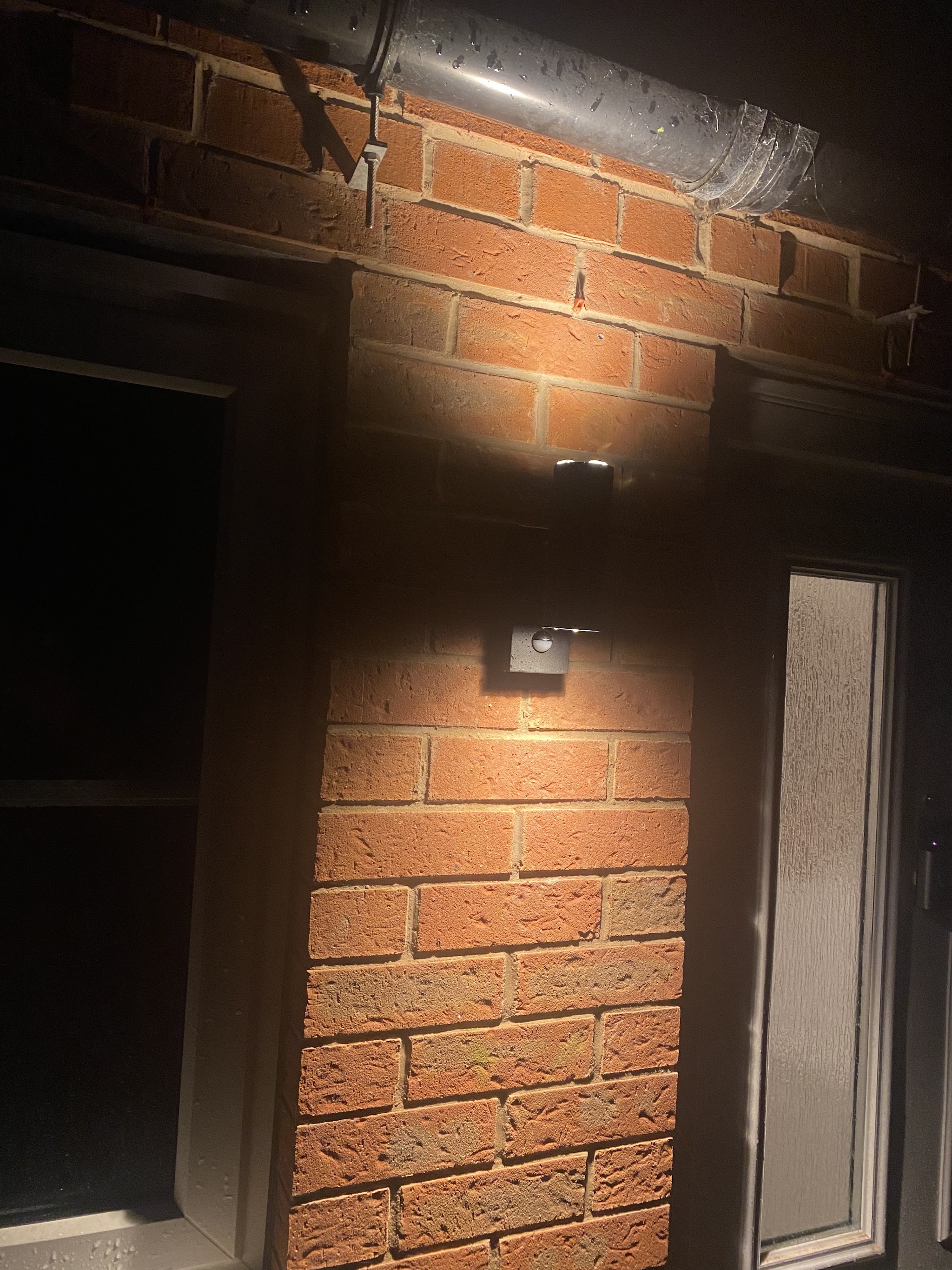 External wall light beside a door, lit at night